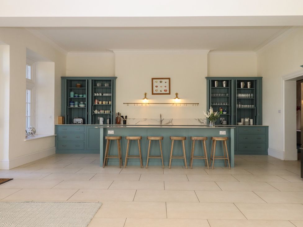 A kitchen with a central island and bar stools at Alston Hall near Mothecombe Beach