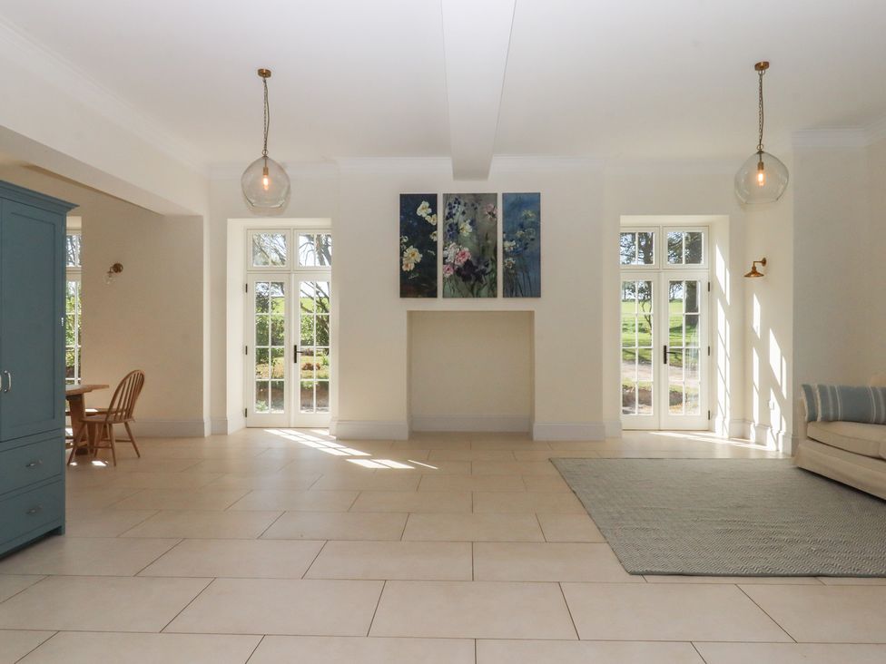 A living room with a dining table and sofa at Alston Hall near Mothecombe Beach