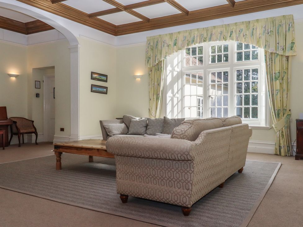 A living room with a sofa, table, and armchair at Alston Hall near Mothecombe Beach