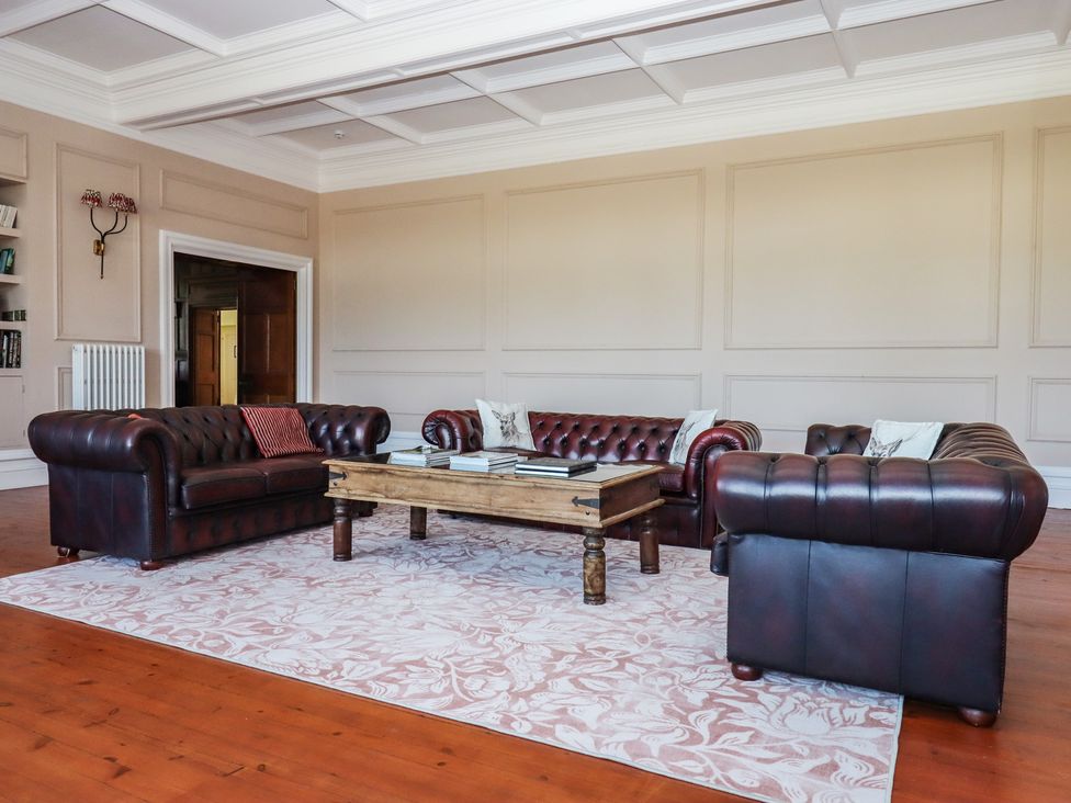 A living room with leather sofas and a wooden coffee table at Alston Hall near Mothecombe Beach