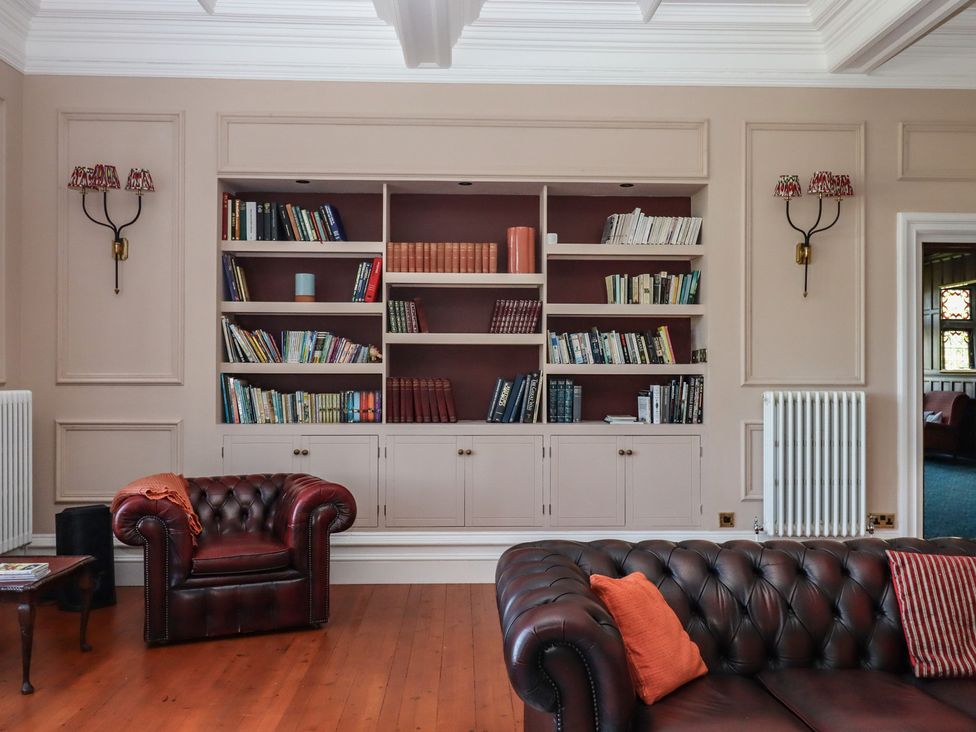 A living room with a bookshelf and an armchair at Alston Hall near Mothecombe Beach