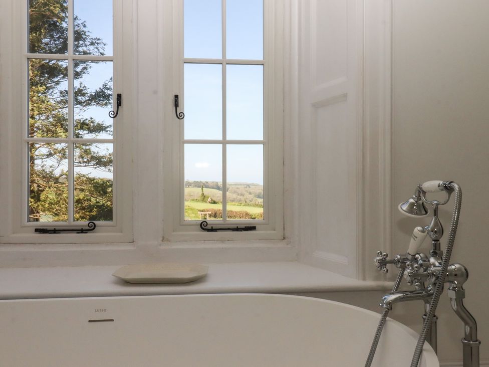 A bathroom with a bathtub and window at Alston Hall near Mothecombe Beach