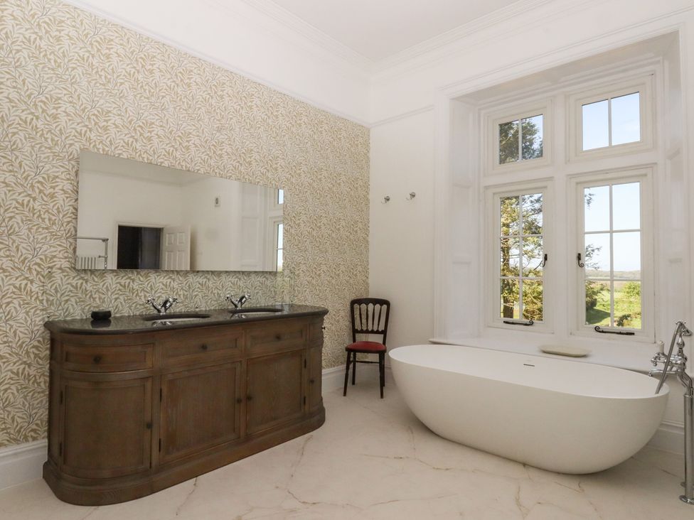 A bathroom with a bathtub, sink, and mirror at Alston Hall near Mothecombe Beach