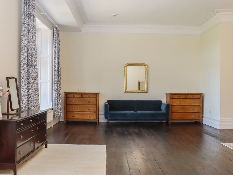 A living room with a sofa and dressers at Alston Hall near Mothecombe Beach