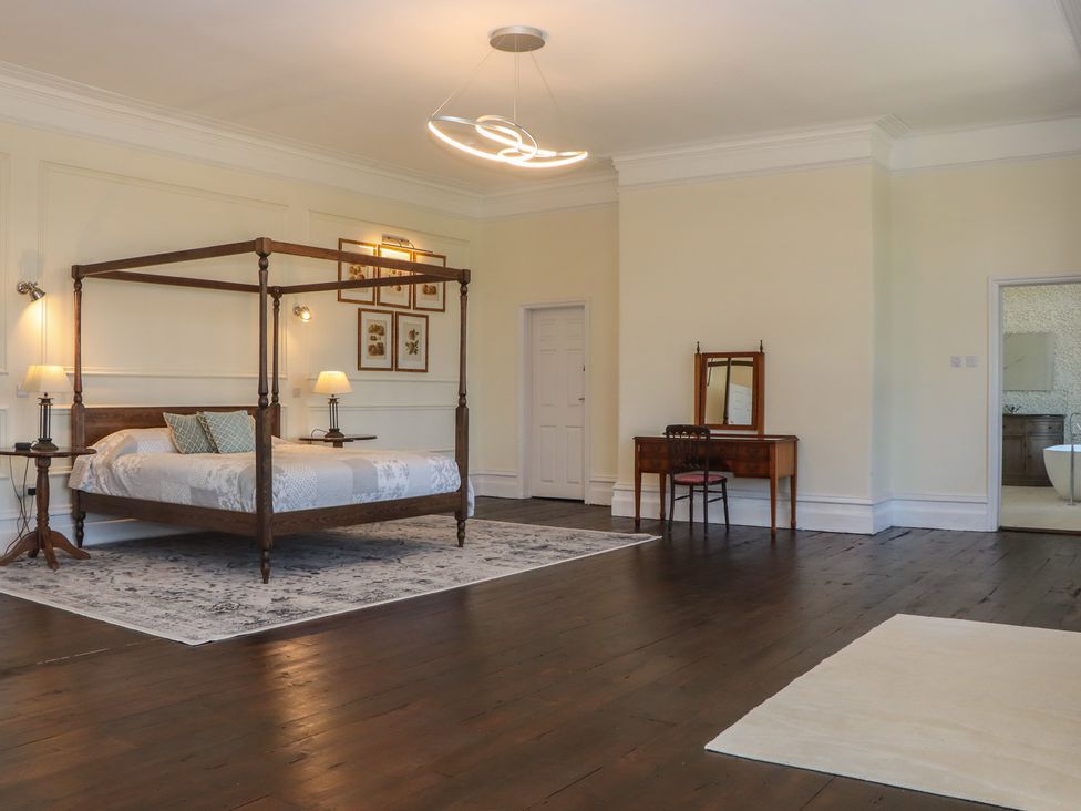 A bedroom with a four-poster bed and a vanity table at Alston Hall near Mothecombe Beach