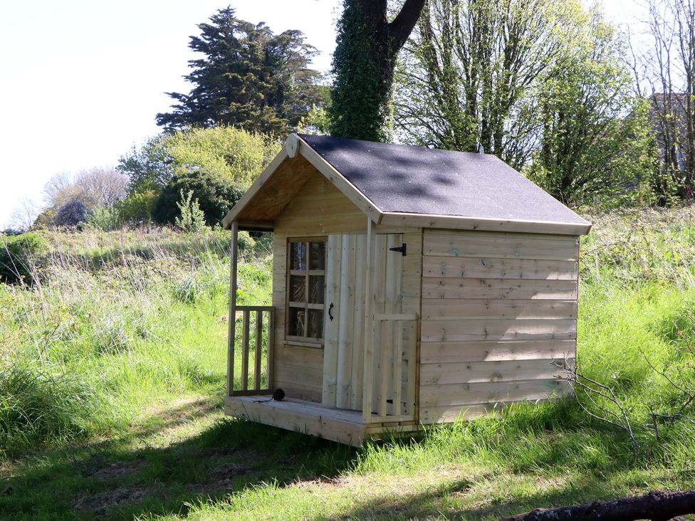 A wooden playhouse in a grassy area at Alston Hall near Mothecombe Beach