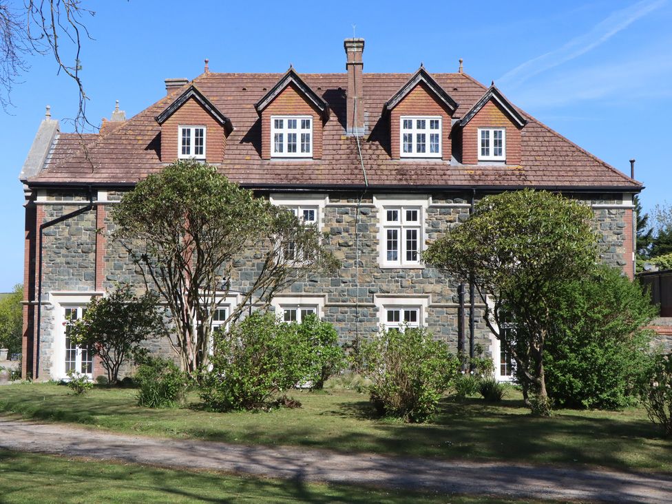 A stone building with multiple windows and trees at Alston Hall near Mothecombe Beach