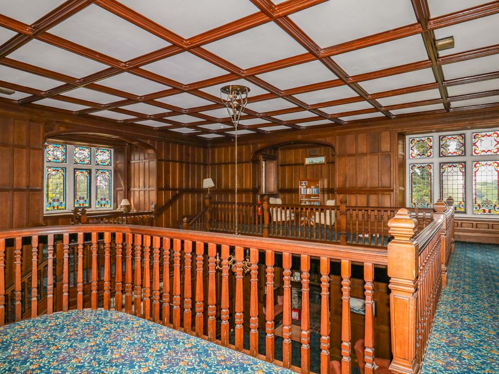 A balcony with wood paneling and stained glass windows at Alston Hall near Mothecombe Beach