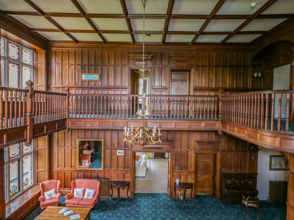 A living room with a staircase and chandelier at Alston Hall near Mothecombe Beach