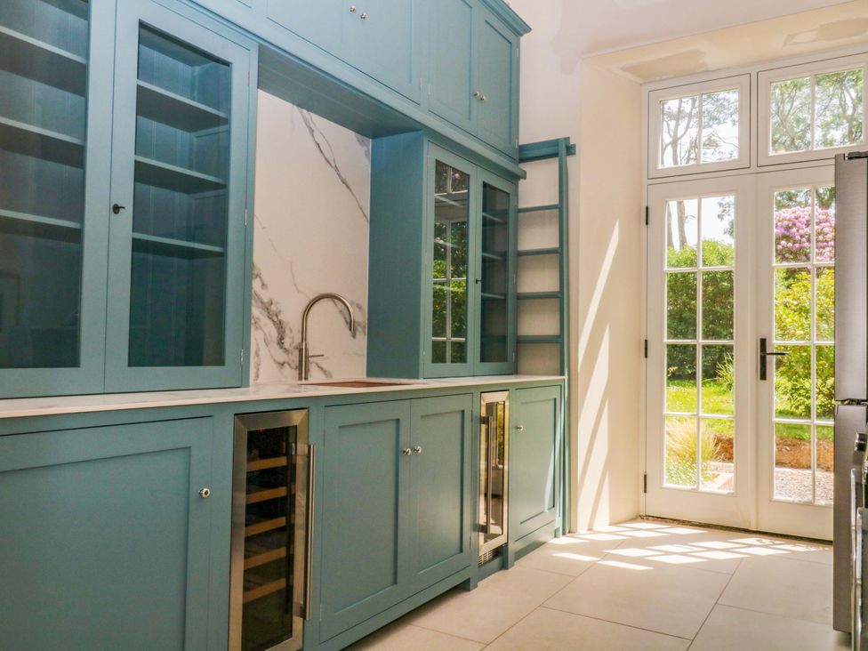 A kitchen with blue cabinets and a sink at Alston Hall near Mothecombe Beach