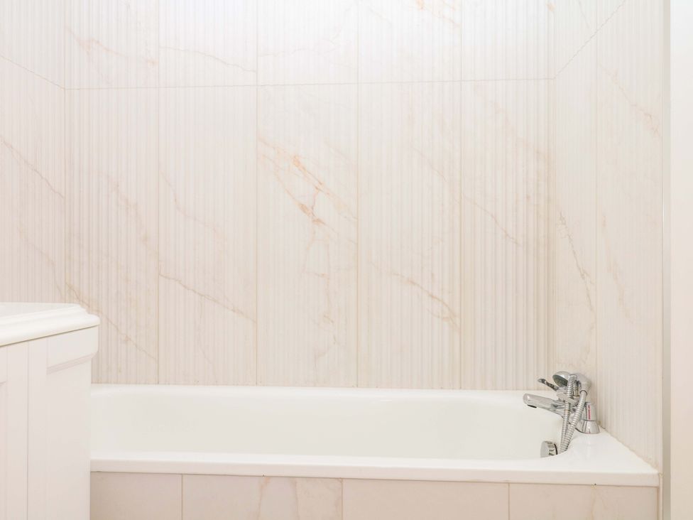 A bathroom featuring a bathtub and wall tiles at Alston Hall near Mothecombe Beach