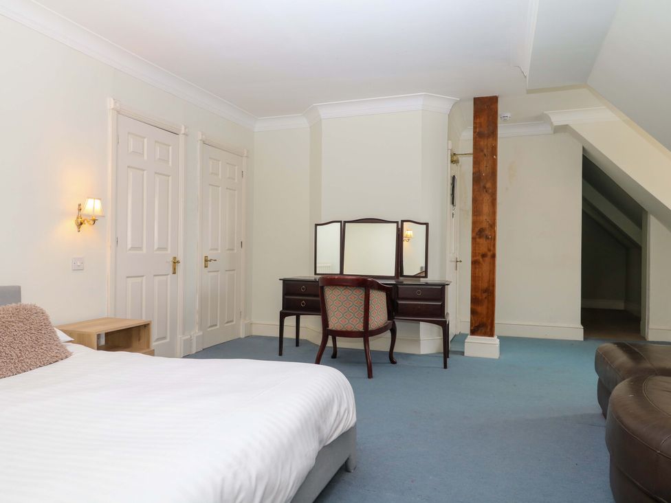 A bedroom featuring a bed, dressing table, and two doors at Alston Hall near Mothecombe Beach