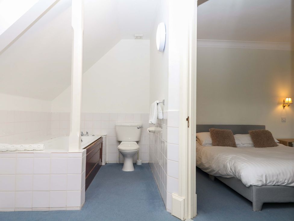 A bathroom with a bathtub and toilet adjoining a bedroom at Alston Hall near Mothecombe Beach
