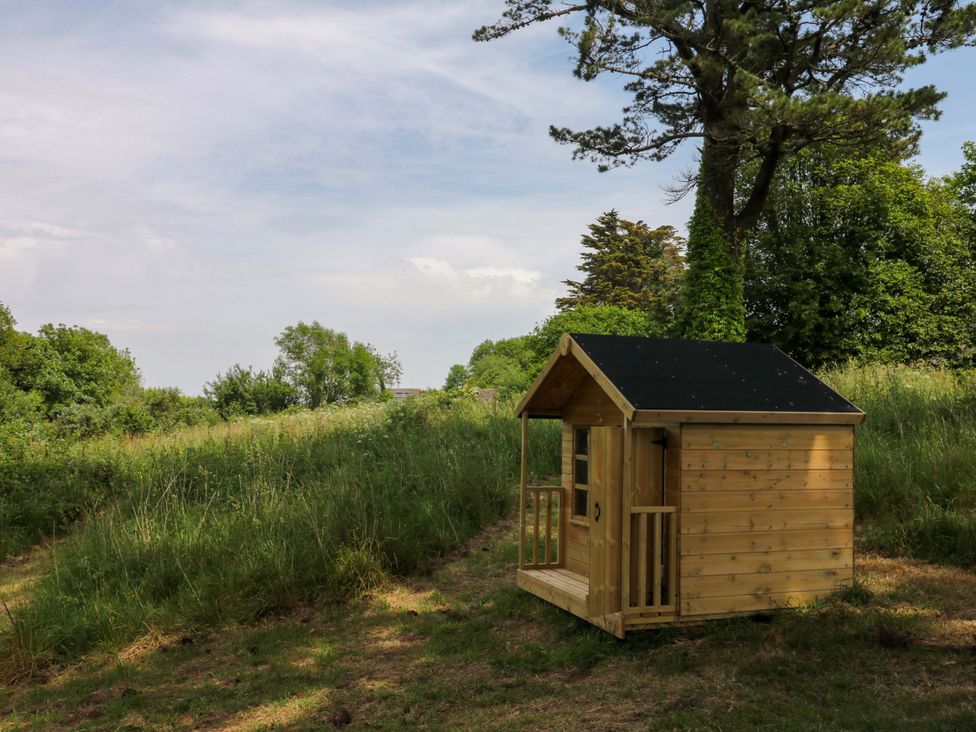 A wooden cabin in a grassy area with trees at Alston Hall near Mothecombe Beach