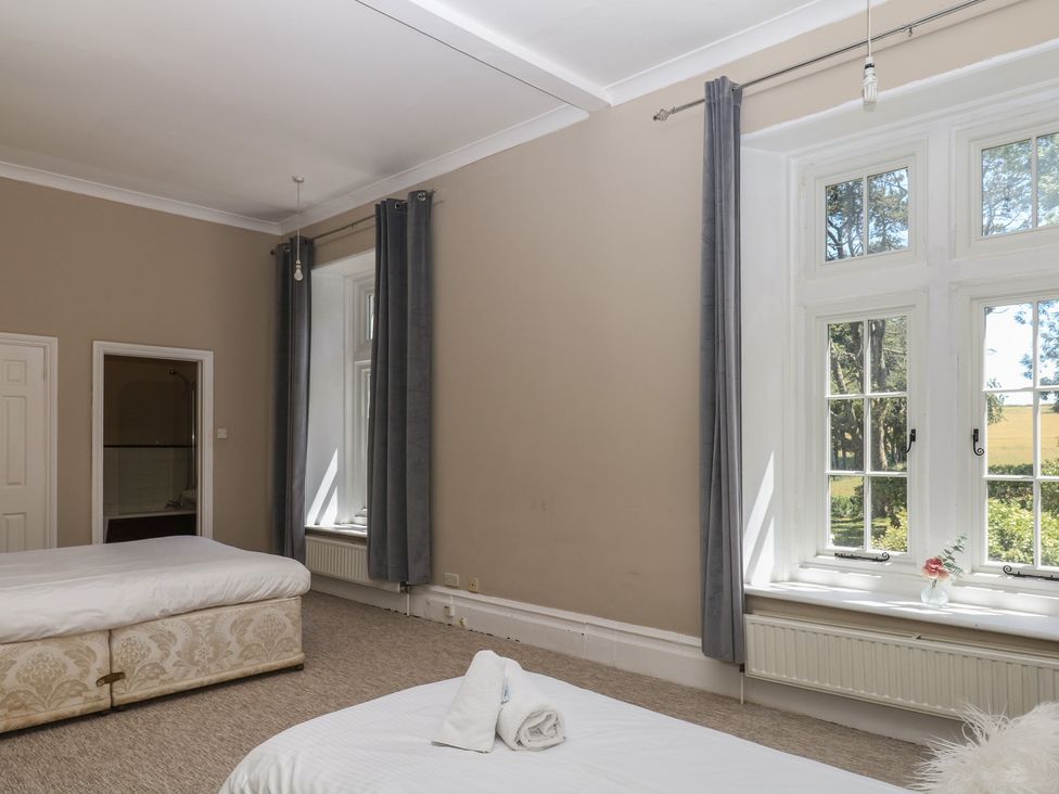A bedroom with beds and windows at Alston Hall near Mothecombe Beach