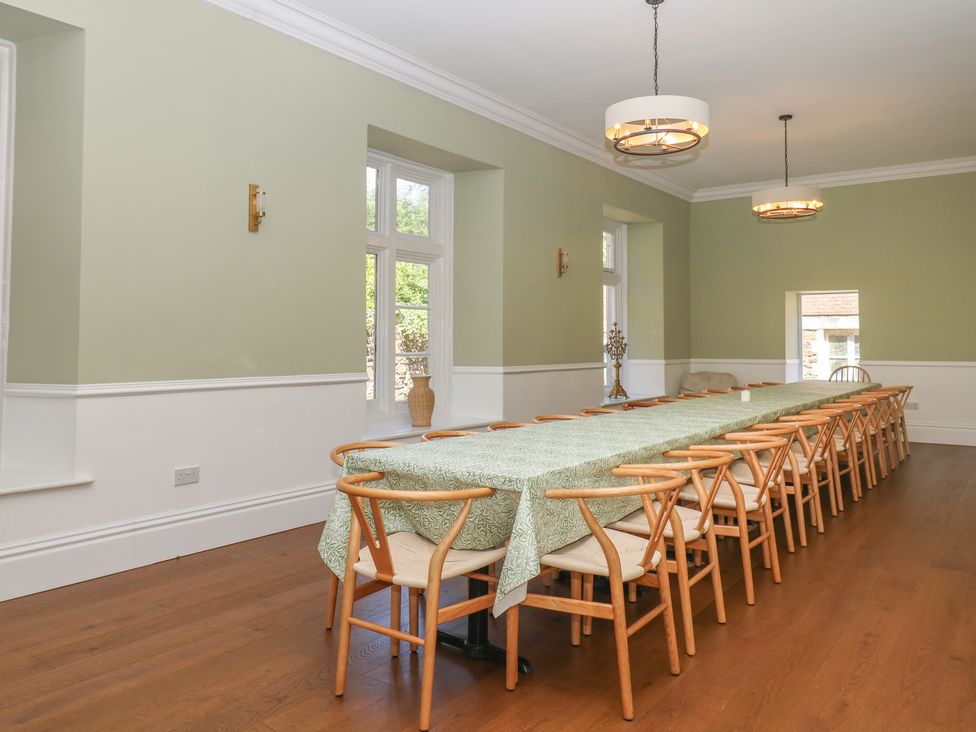 A dining room with a long table and chairs at Alston Hall near Mothecombe Beach