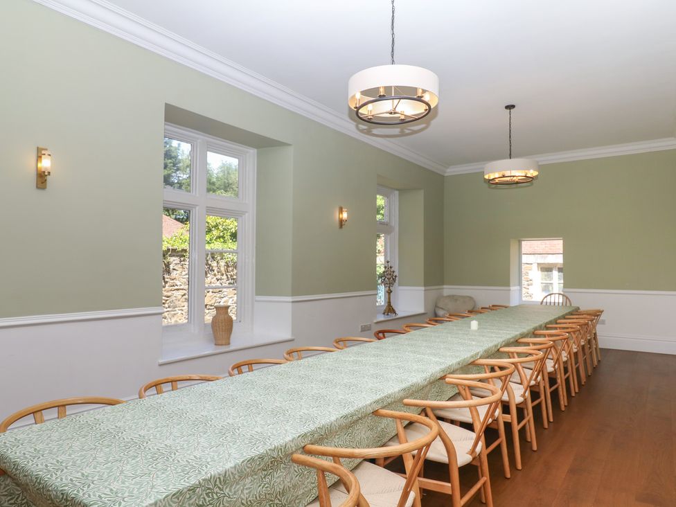 A dining room with a long table and chairs at Alston Hall near Mothecombe Beach