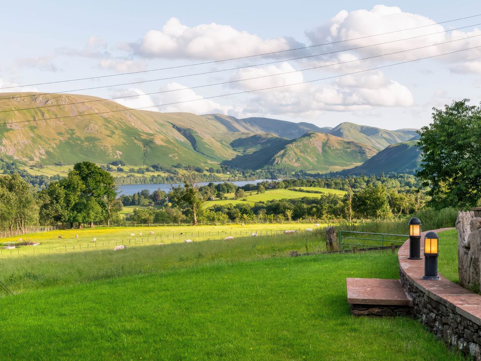 A view of hills and a lake with trees and grass at Bank Barn, Wreay in Watermillock