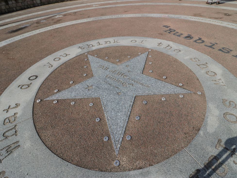 A star with inscriptions in a concrete outdoor area at Cockle Bay Cottage, Heysham