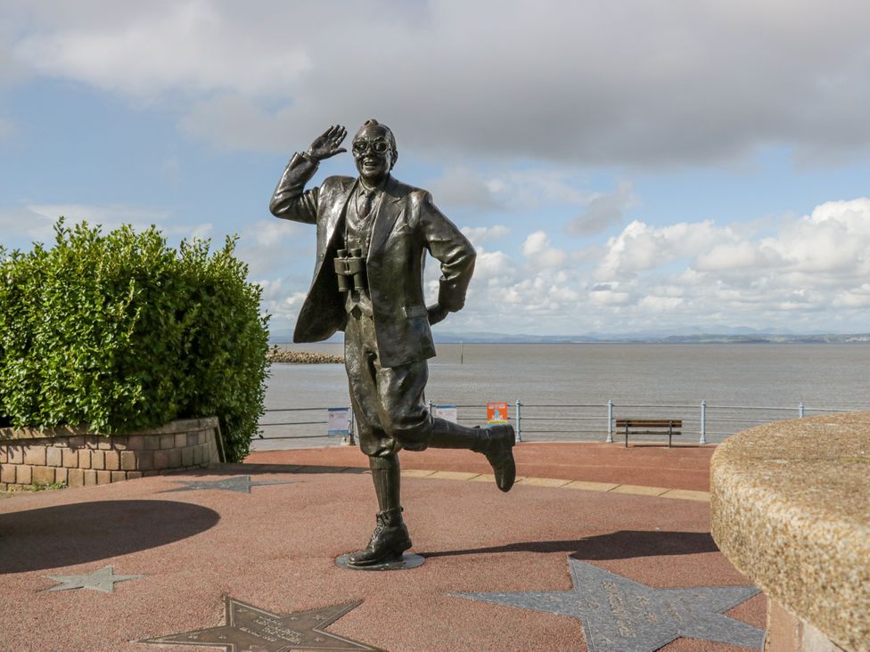 A statue of a man waving near water at Cockle Bay Cottage in Heysham