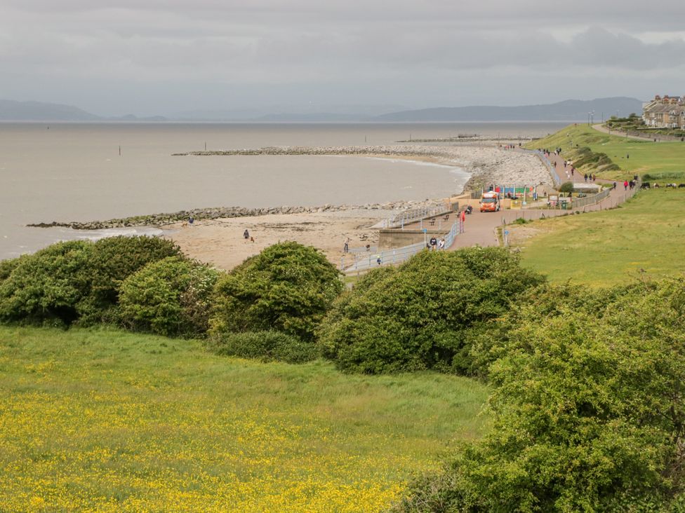 A beach area with people walking along the promenade at Cockle Bay Cottage, Heysham