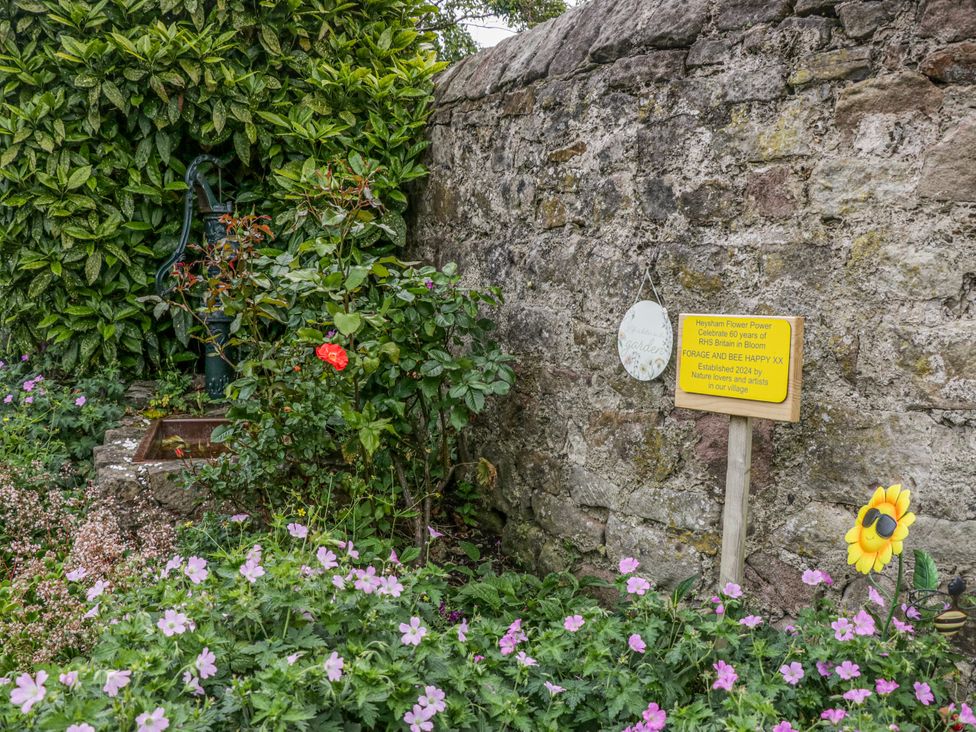 A garden with a water pump and flowering plants at Cockle Bay Cottage in Heysham
