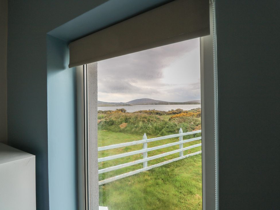 A window with a view of the water and grass at No.5 Beach Cottages, Keel, County Mayo