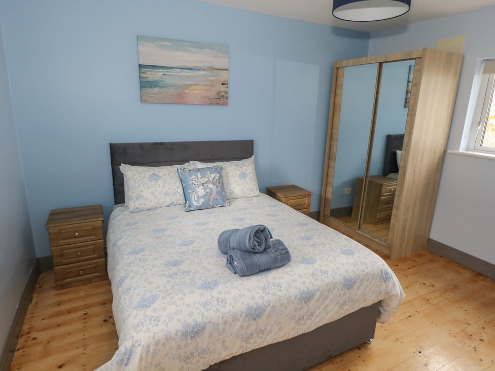 A bedroom with a bed and a mirror wardrobe at No.5 Beach Cottages in Keel, County Mayo