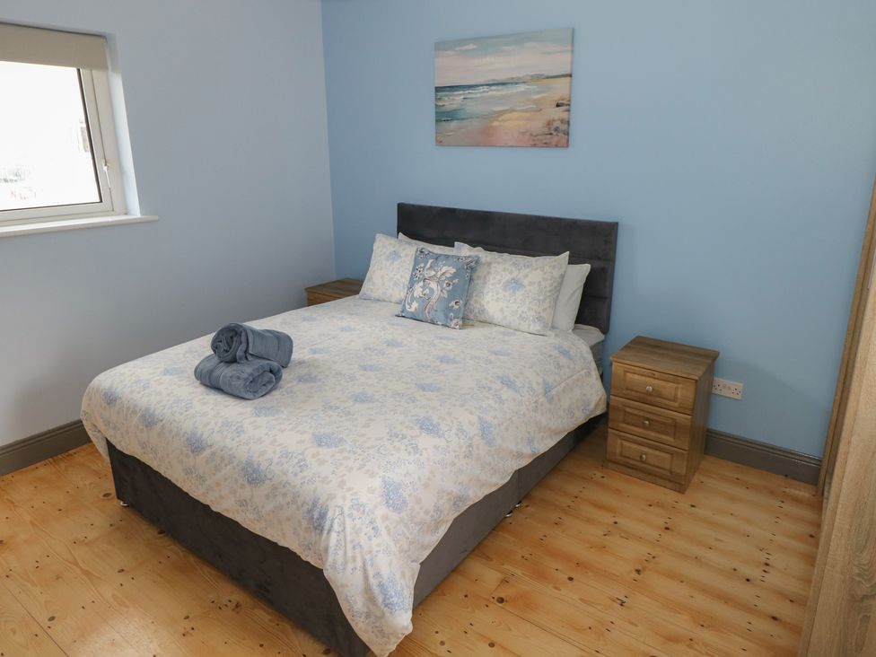 A bedroom with a bed, nightstand, and window at No.5 Beach Cottages in Keel, County Mayo