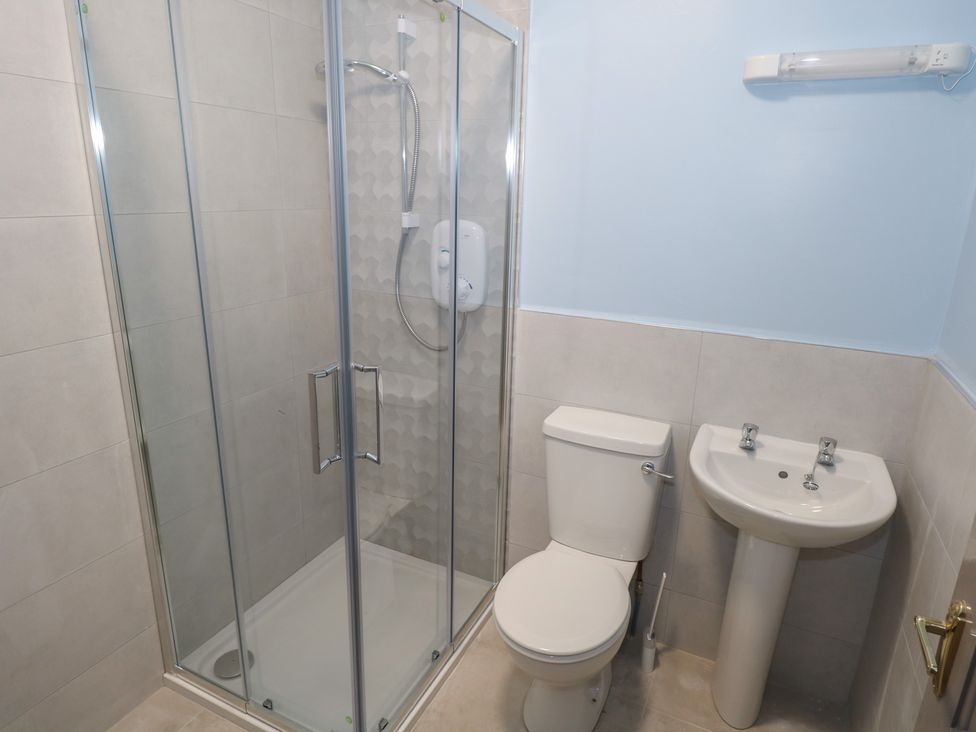 A bathroom with a shower, toilet, and sink at No.5 Beach Cottages in Keel, County Mayo
