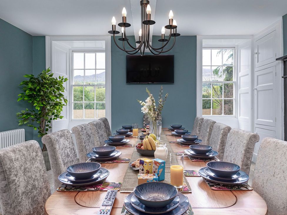 A dining room with a long table set for a meal at Snowdonia Manor in Dolgellau