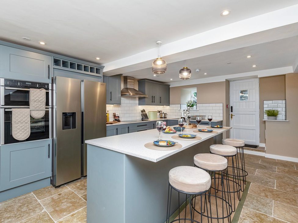 A kitchen with an island and bar stools at Snowdonia Manor in Dolgellau