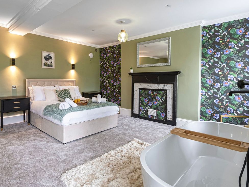A bedroom featuring a bed, nightstands, a fireplace, and a bathtub at Snowdonia Manor in Dolgellau