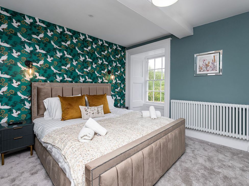A bedroom with a bed and decorative wallpaper at Snowdonia Manor in Dolgellau
