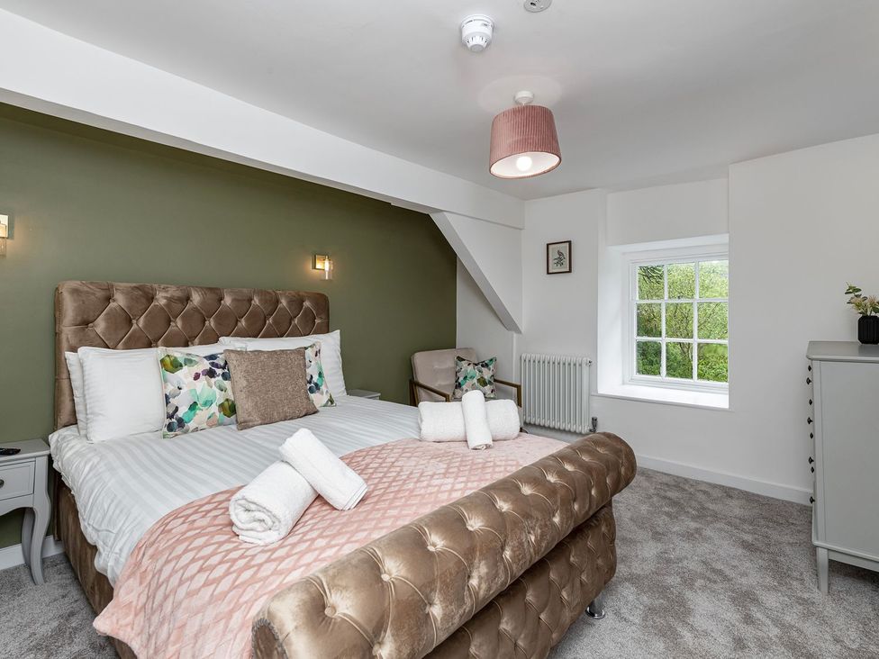 A bedroom with a bed and an armchair at Snowdonia Manor in Dolgellau