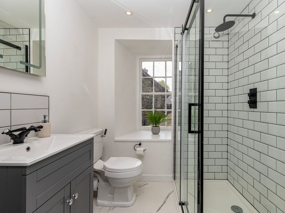 A bathroom with a sink, toilet, shower and window at Snowdonia Manor in Dolgellau