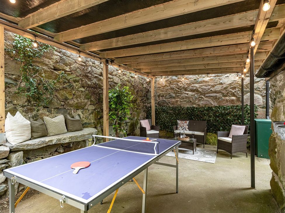 An outdoor seating area with a ping pong table and stone wall at Snowdonia Manor in Dolgellau