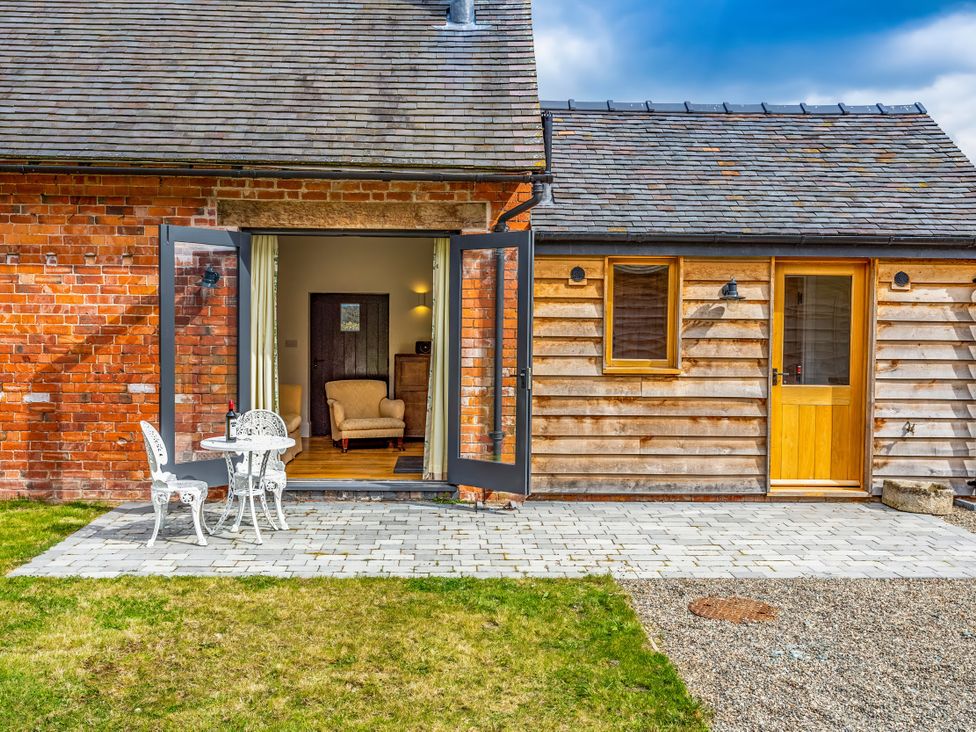 An outdoor area with a table and chairs in front of a house at Johnsons Smallholding in Market Drayton