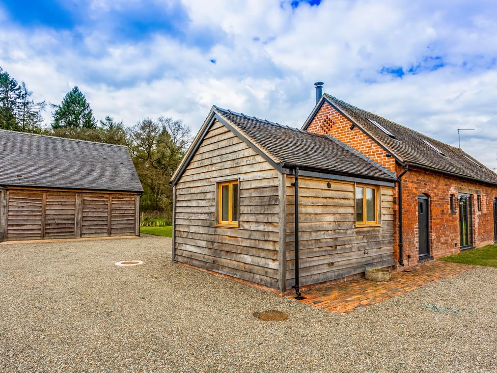 A building with a wooden exterior and gravel driveway at Johnsons Smallholding in Market Drayton