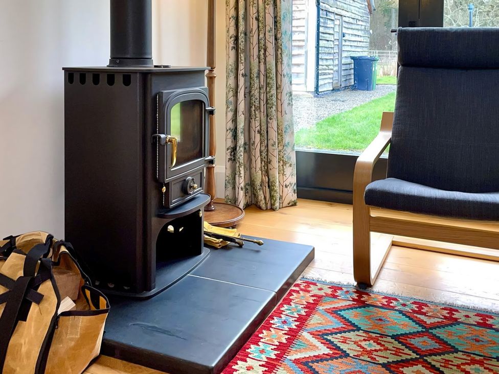A living room with a stove and chair at Johnsons Smallholding Market Drayton