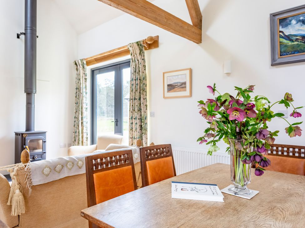 A dining room with a wooden table and vase of flowers at Johnsons Smallholding in Market Drayton