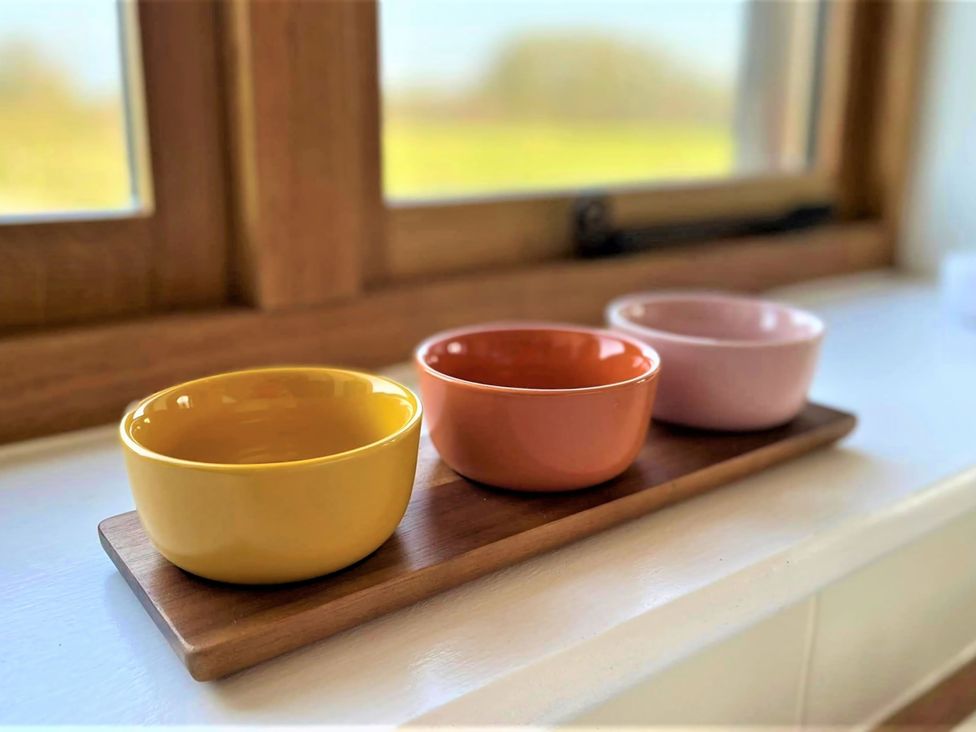 Three bowls on a wooden tray by a window at Johnsons Smallholding Market Drayton