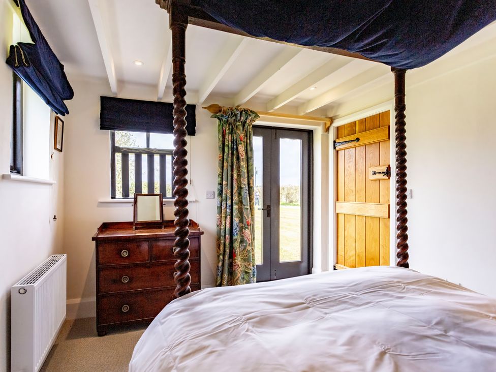 A bedroom with a four-poster bed and a dresser at Johnsons Smallholding in Market Drayton