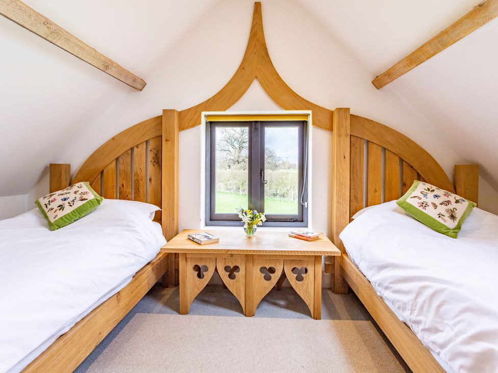A bedroom with two beds, a table, and a window at Johnsons Smallholding in Market Drayton