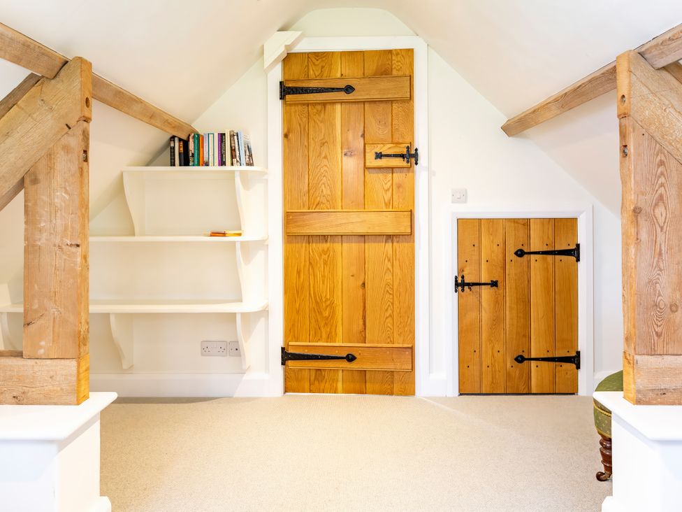 An attic with books on shelves and wooden doors at Johnsons Smallholding in Market Drayton