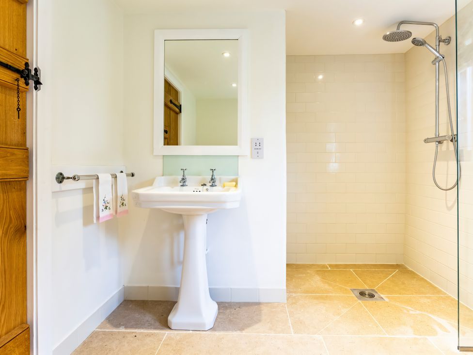 A bathroom with a sink, mirror, and shower at Johnsons Smallholding in Market Drayton