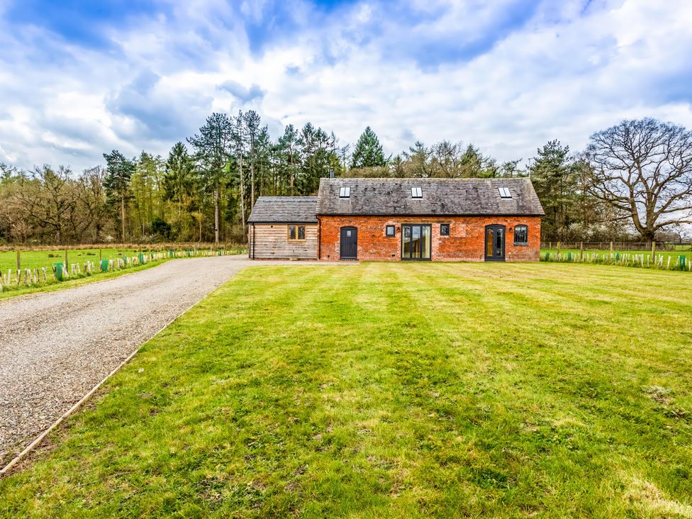 A house with a gravel driveway and trees at Johnsons Smallholding in Market Drayton