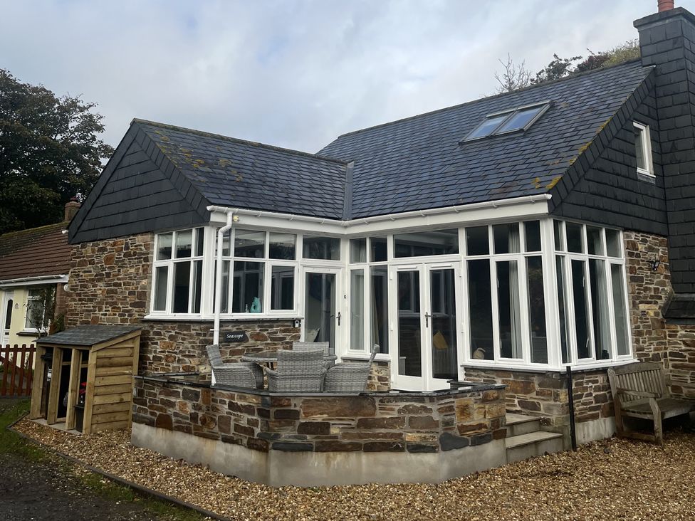 An outdoor view of a house with a stone wall and windows at Seascape in Kingsand