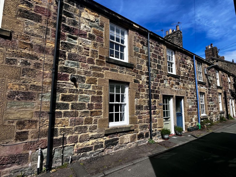 A row of stone cottages with sash windows and doors on a narrow street at Aln Cottage Alnmouth