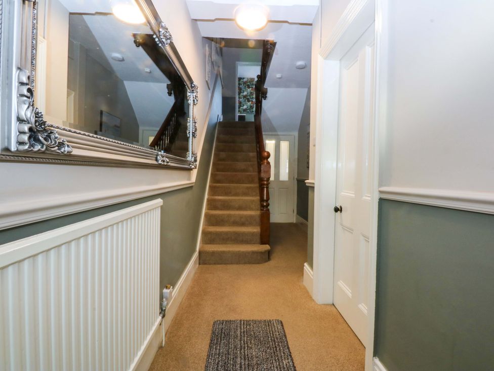 A hallway with a staircase and a mirror at Curzon Heights in Llandudno